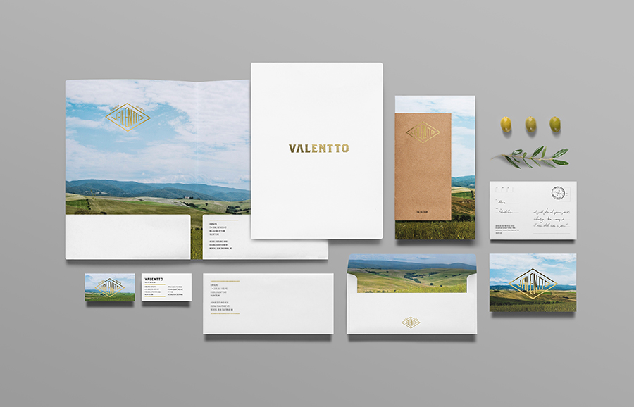 Logo and stationery set with gold foil and photographic landscape detail designed by Anagrama for olive oil brand Valentto