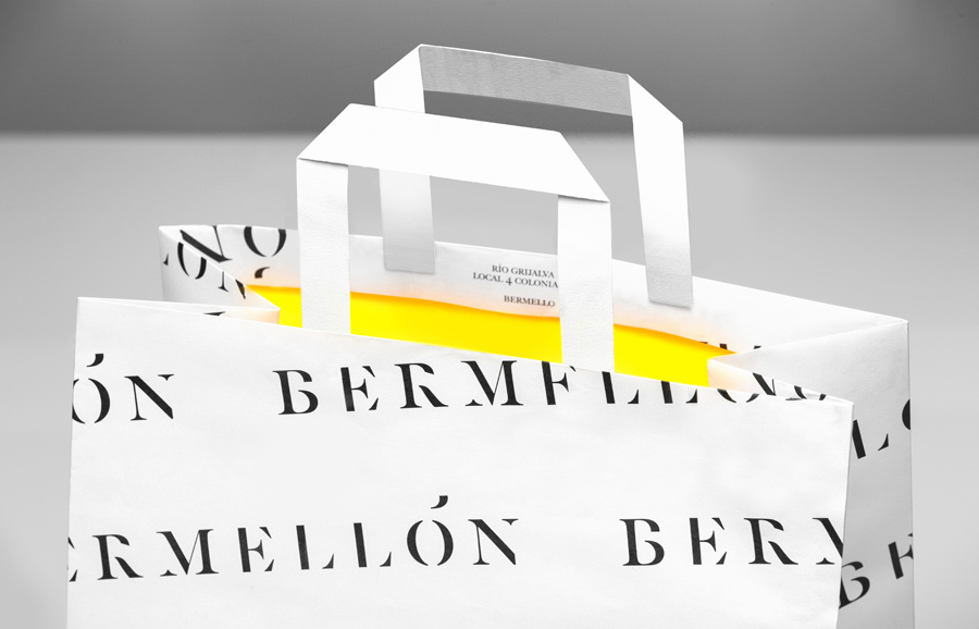 Paper bag with white exterior and bright yellow interior for confectionery shop Bermellón designed by Anagrama