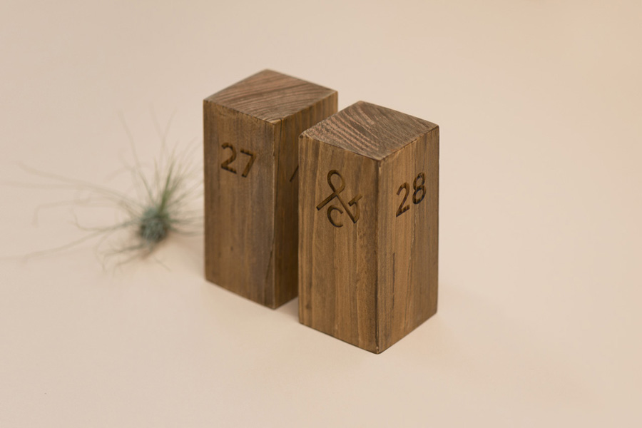 Logo, wood carved table numbers designed by Acre for co-branded retail partnership Pact