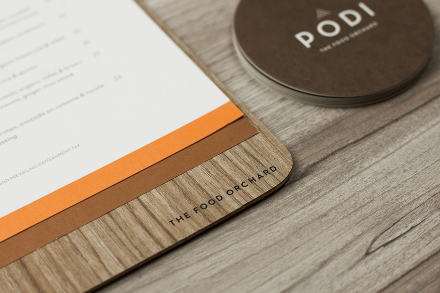 Logotype, menu with wood detail and coasters designed by Bravo Company for Singapore-based organic restaurant Podi