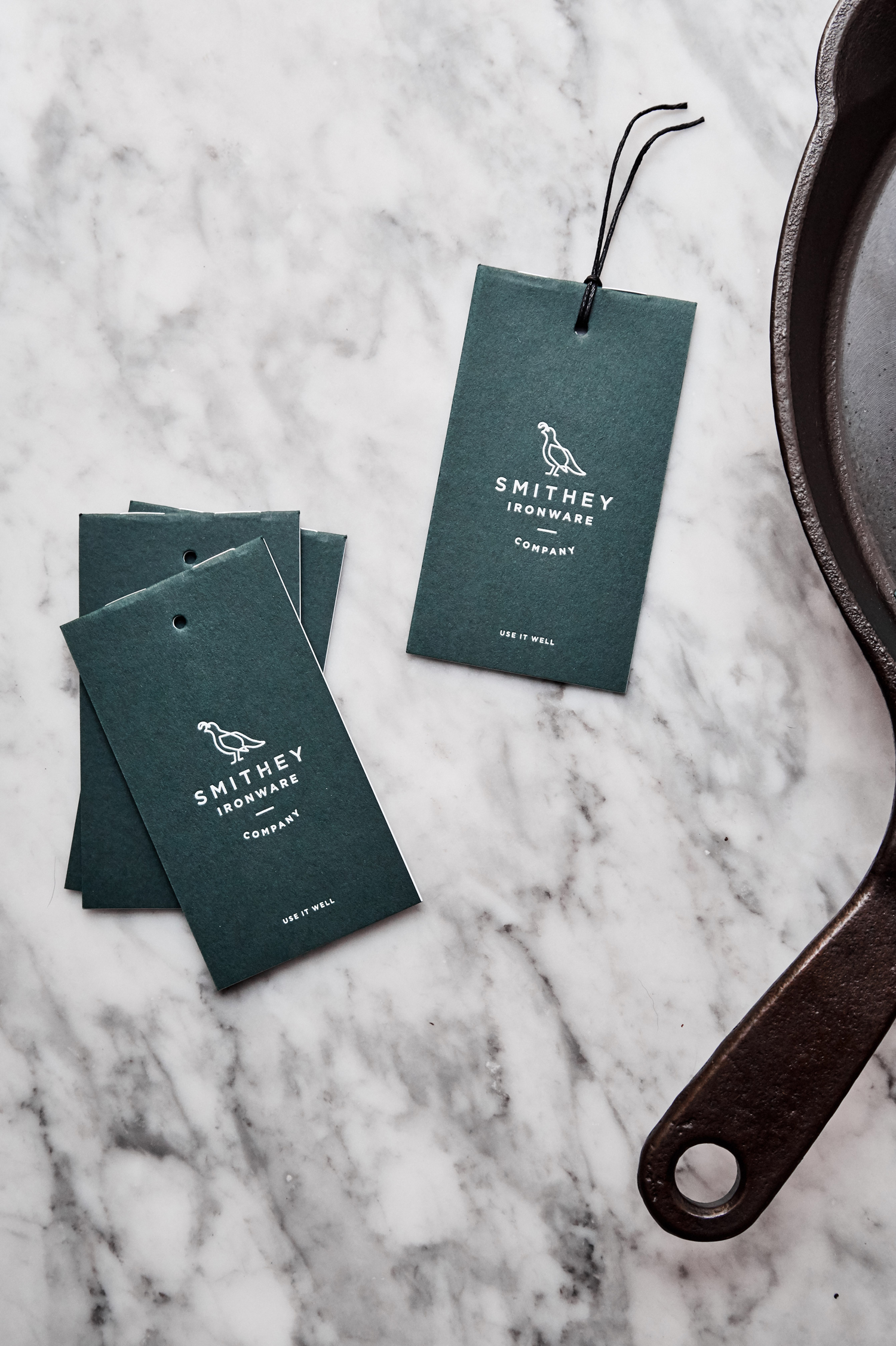 Brand identity and tags with green paper and white ink detail for Smithey Ironware Company by Charleston based Stitch, United States